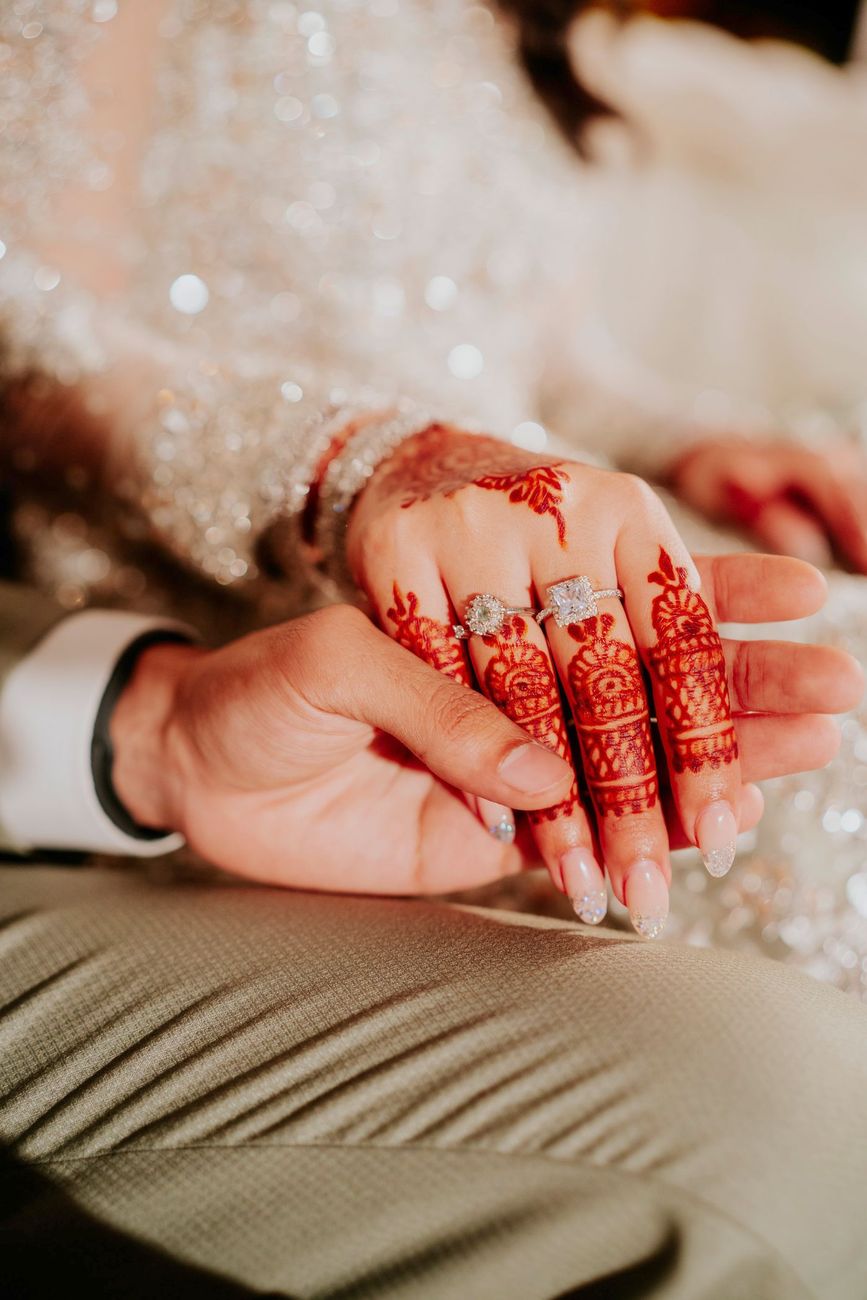 Close-up detail of bride and groom's joined hands, her henna and engagement rings visible, Maham & Aurangzeb's wedding