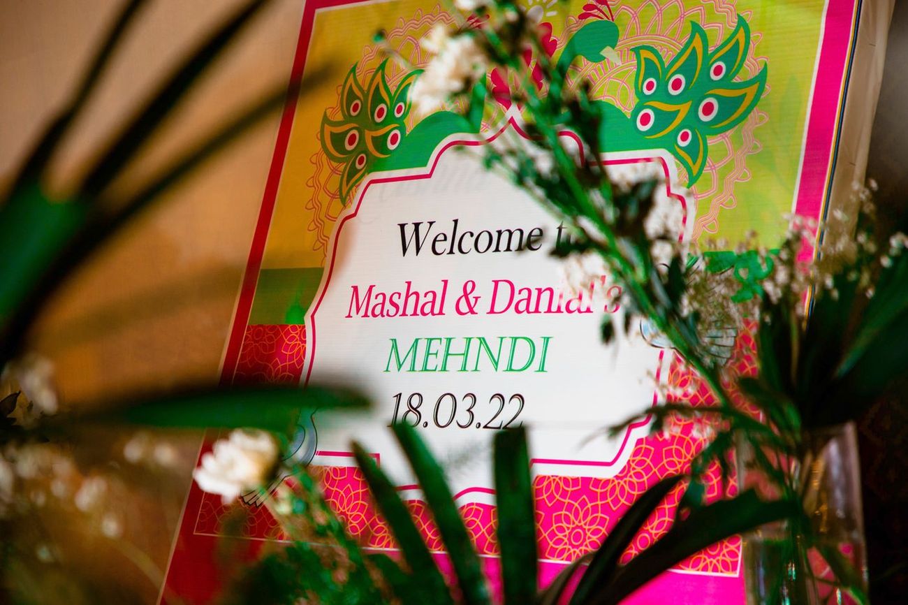 Welcome sign for Mashal and Danial's mehndi, dated 18.03.22, framed by green leaves