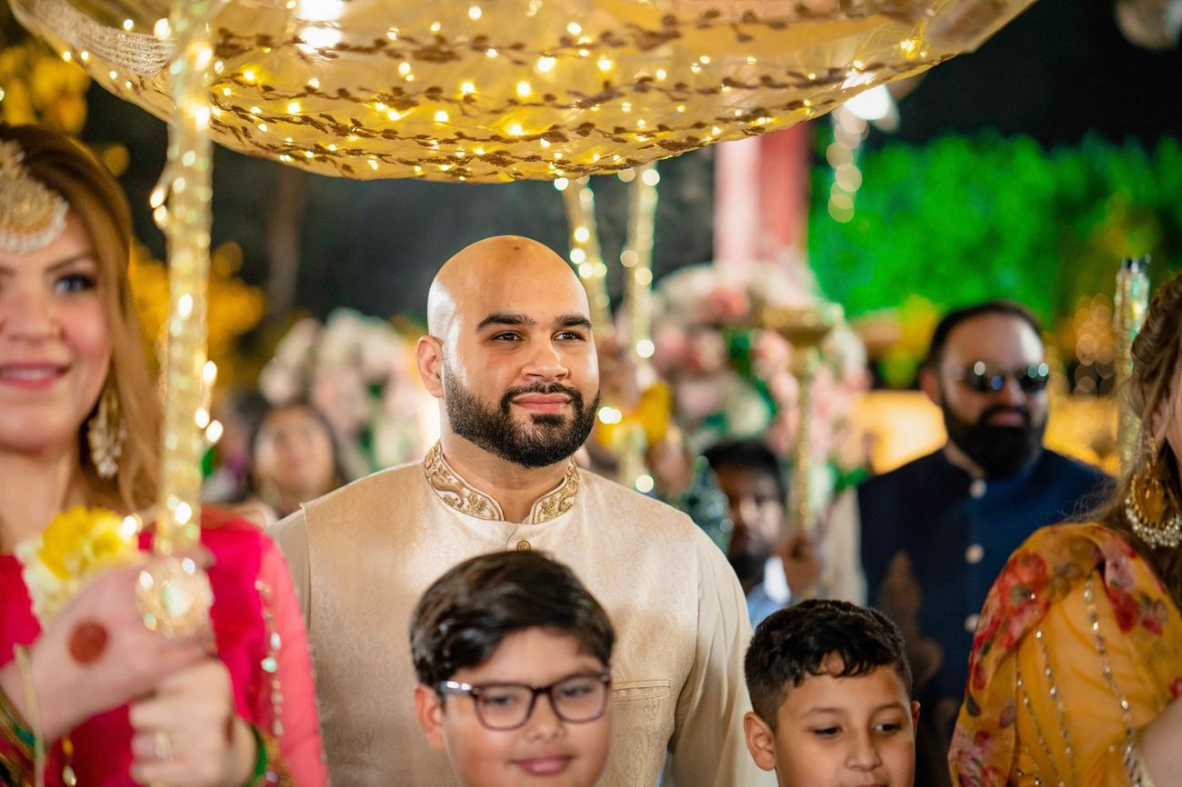 Groom standing beneath a decorated canopy carried by family members during the mehndi procession, Mashal & Danial's wedding