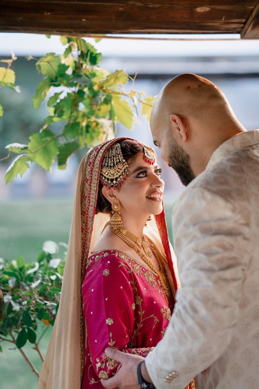 Bride and groom sharing a close moment beneath a wooden gazebo roof at golden hour, Mashal & Danial's wedding