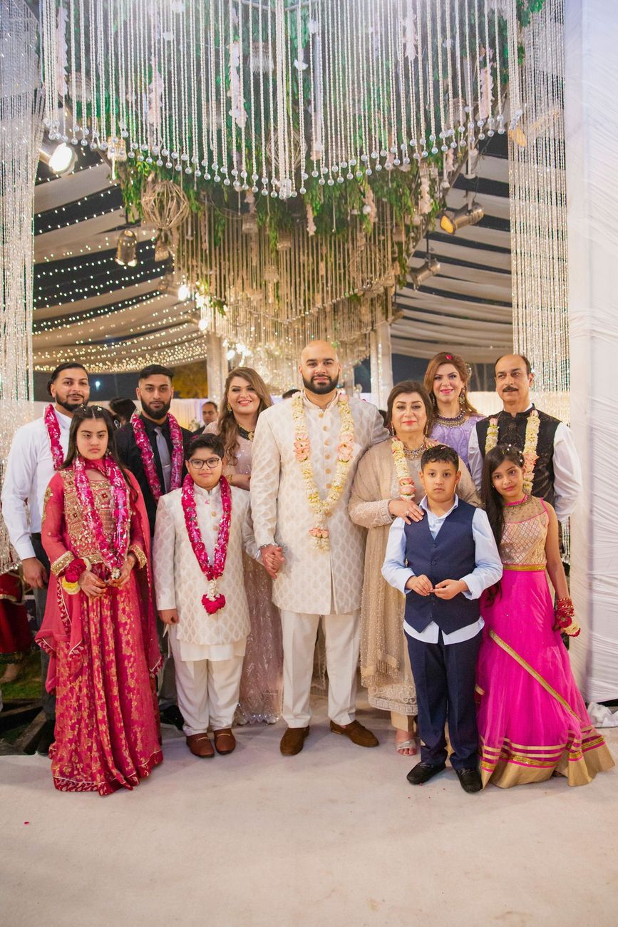 Groom's extended family group photo wearing flower garlands at the reception, Mashal & Danial's wedding