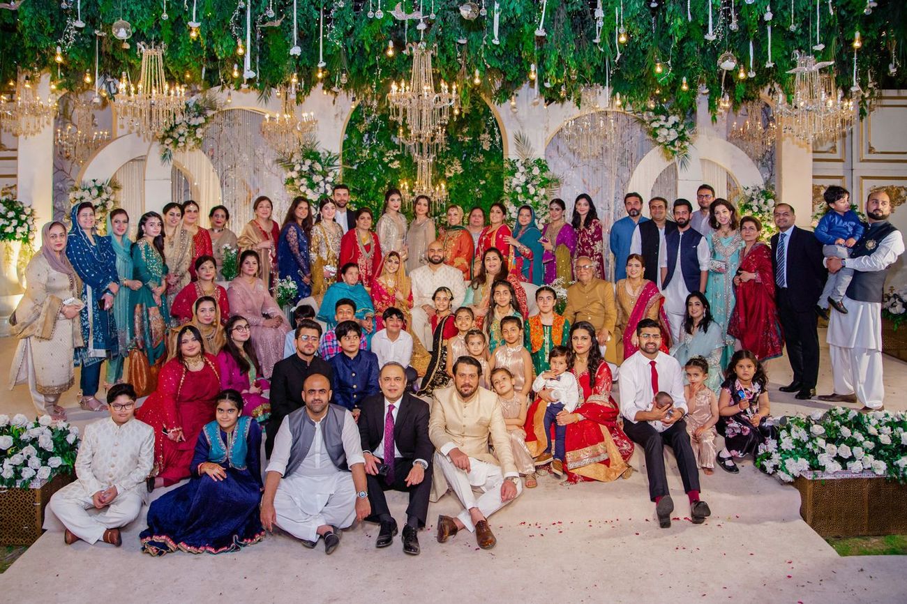 Massive extended family group photo at the reception, bride and groom seated in the center, Mashal & Danial's wedding