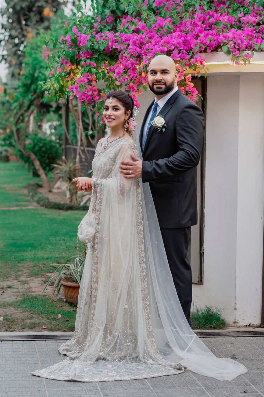 Bride and groom standing together beneath a bougainvillea-covered archway, Mashal & Danial's wedding