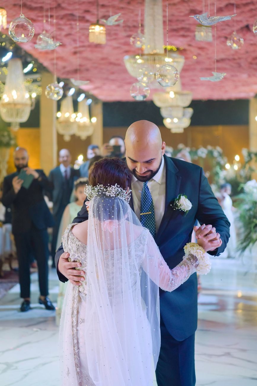 Bride and groom dancing together at the walima beneath a pink ceiling installation, Mashal & Danial's wedding