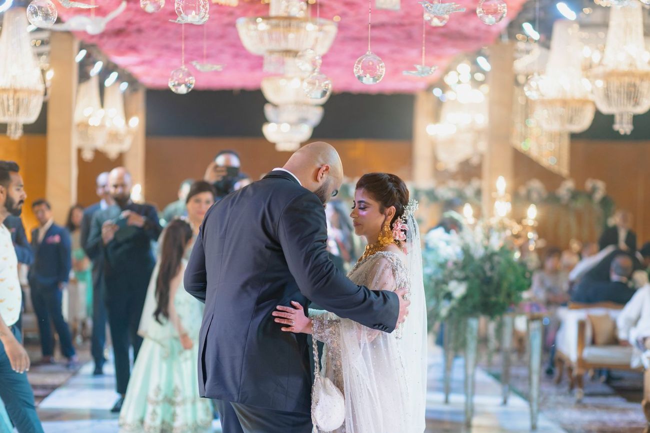 Bride and groom dancing together at the walima reception, surrounded by guests and chandeliers, Mashal & Danial's wedding