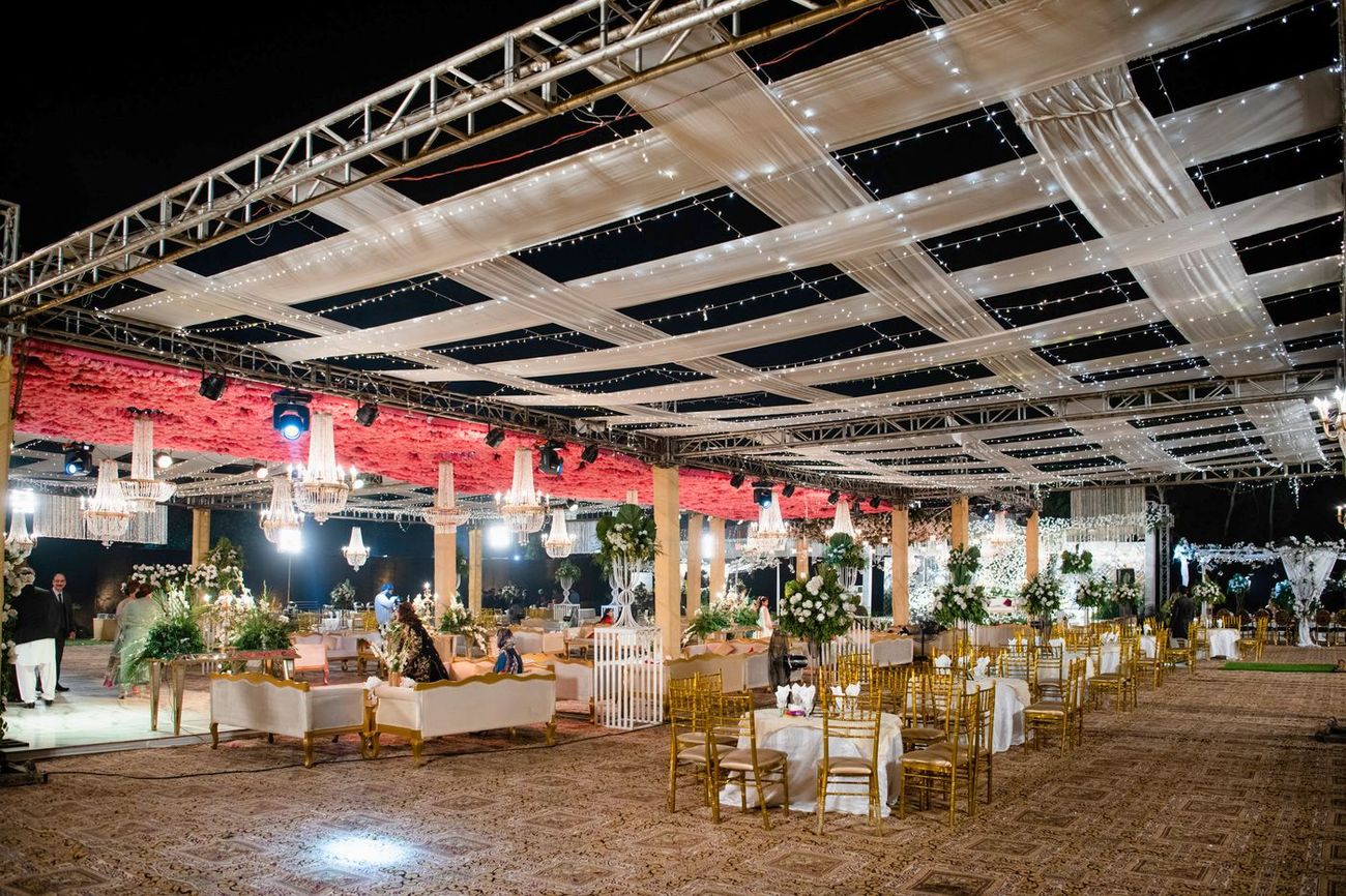 Wide night shot of the walima reception lounge area with gold chiavari chairs and floral centerpieces, Mashal & Danial's wedding