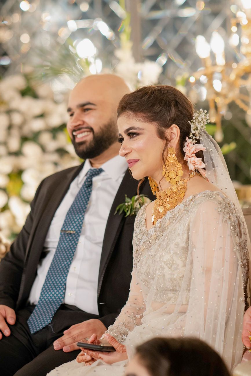 Bride and groom seated together at the walima, bride wearing dramatic gold coin jewelry, Mashal & Danial's wedding
