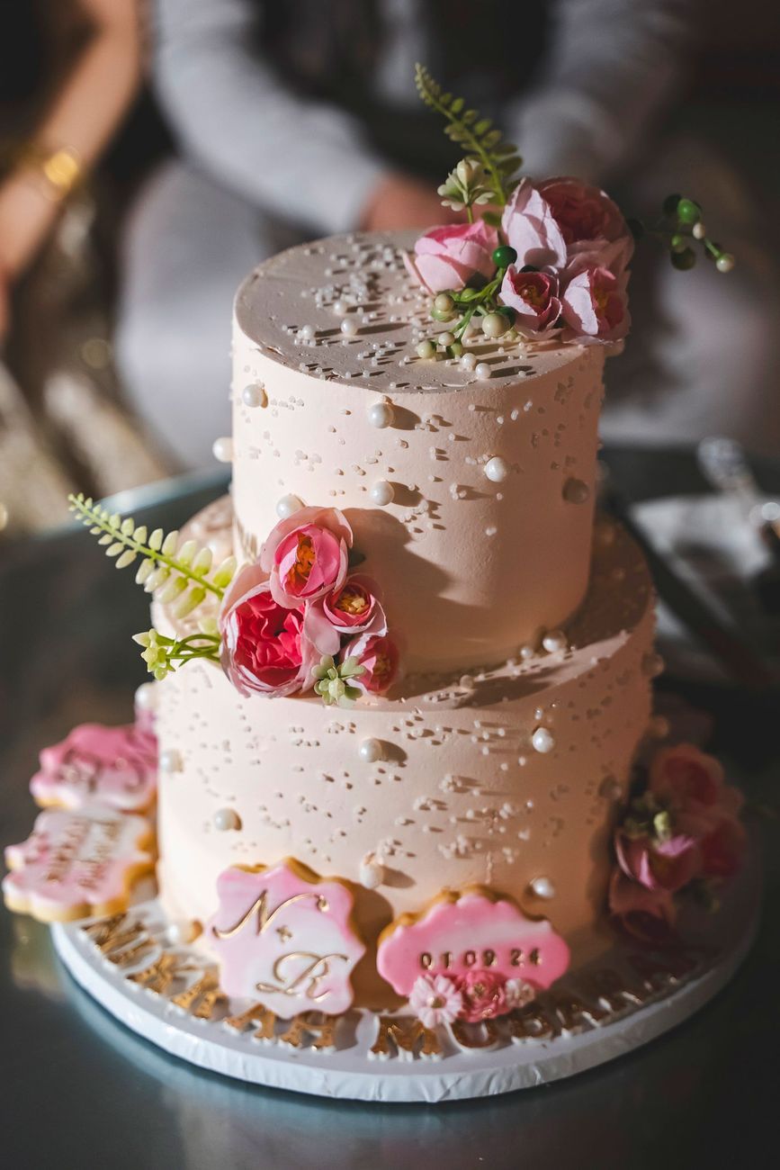 Detail shot of the two-tier wedding cake decorated with sugar flowers and the couple's initials and wedding date, Nayha & Rafay's wedding in Islamabad