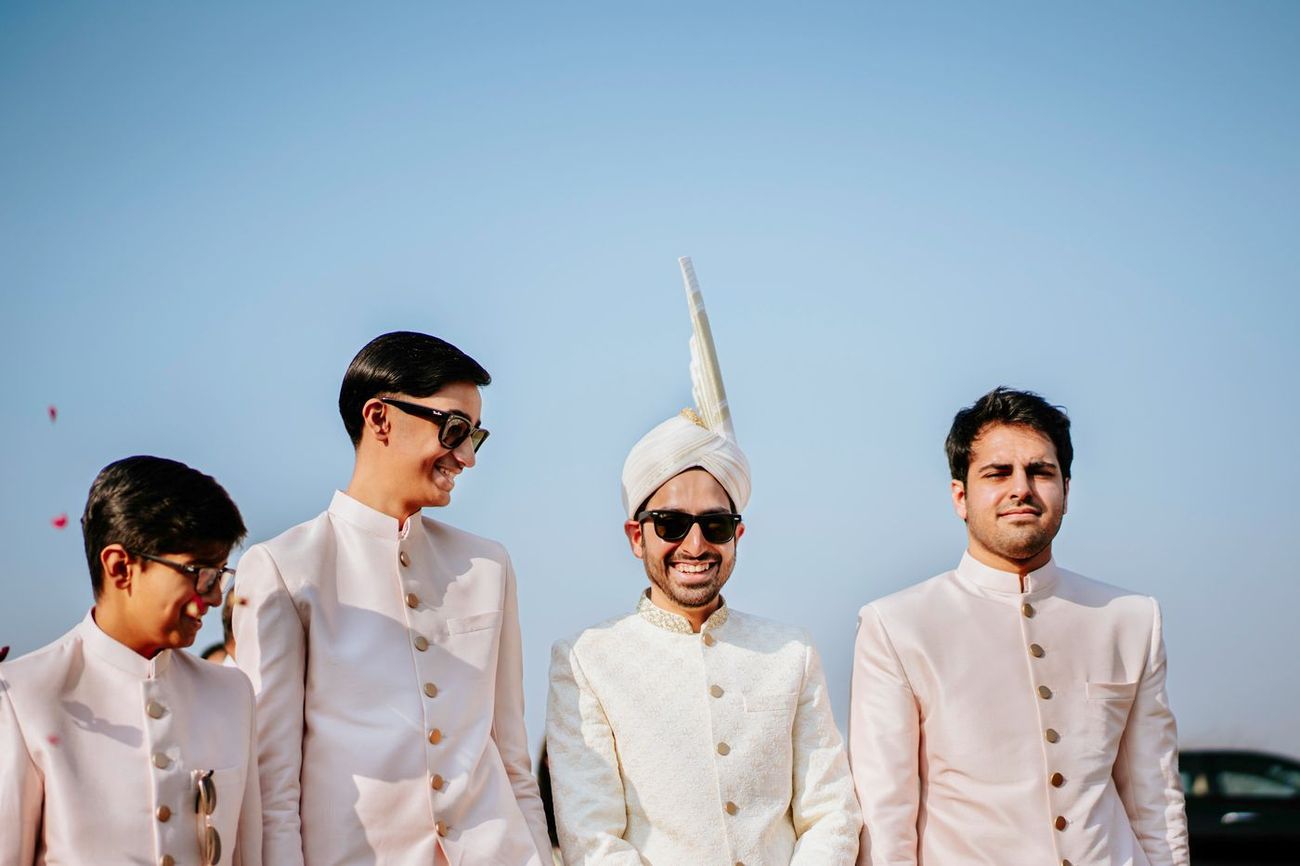 Groom smiling with his groomsmen against a clear blue sky, Samar & Anoosh's wedding