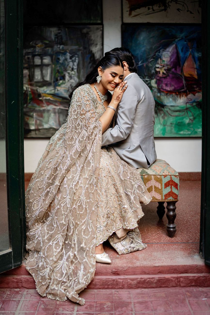 Bride smiling against the groom's shoulder, seated together in a doorway flanked by colorful abstract paintings