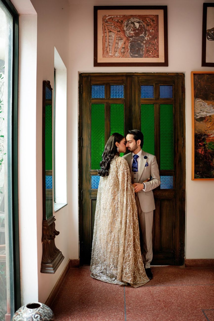 Couple embracing nose to nose in front of a stained-glass wooden door at the art studio
