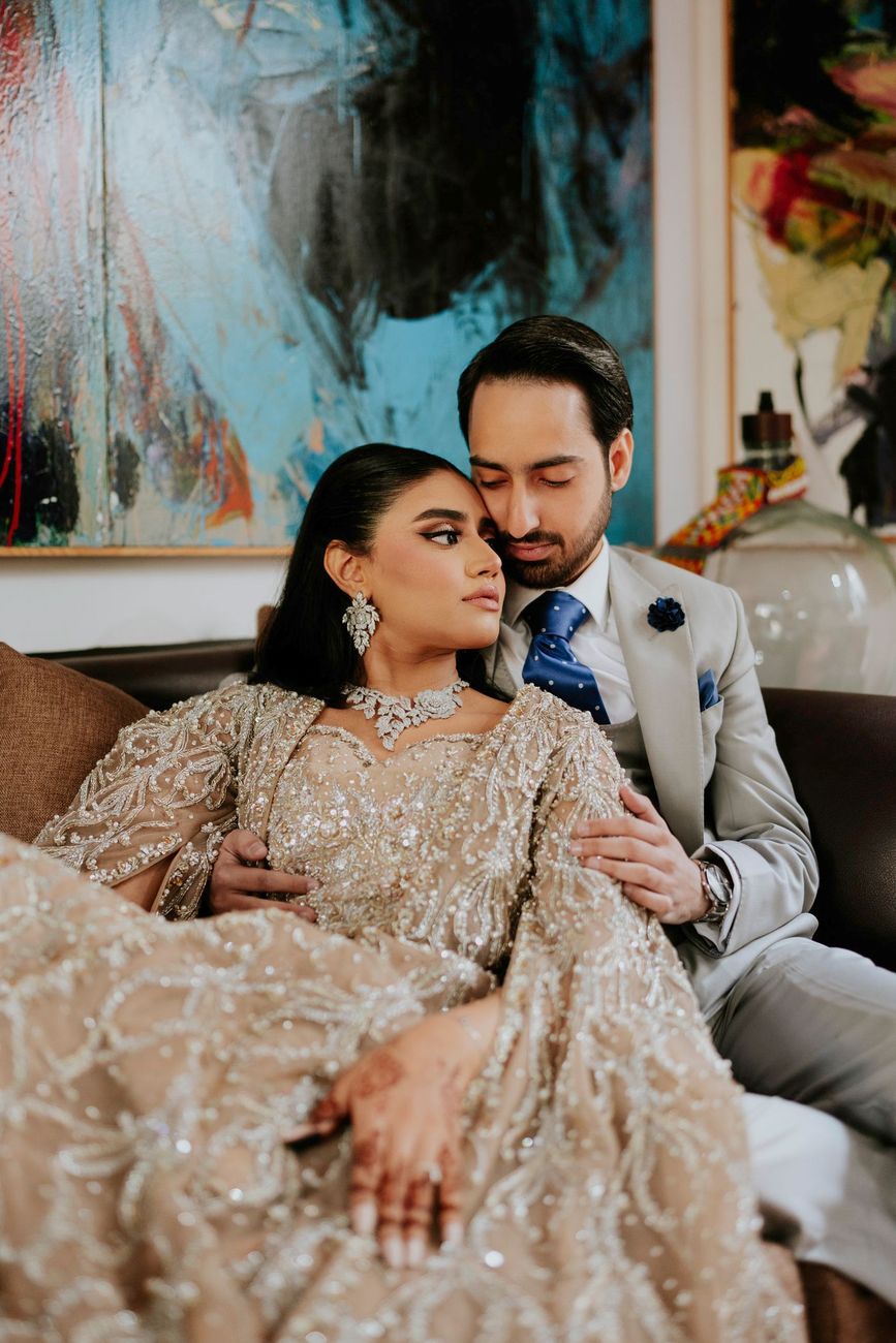 Close-up of the bride resting against the groom's chest, surrounded by large abstract paintings
