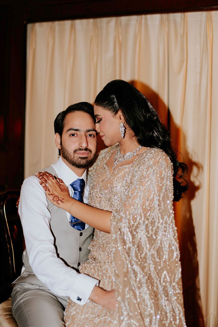 Close-up of the bride and groom together in the hotel suite, her hand on his shoulder, foreheads close