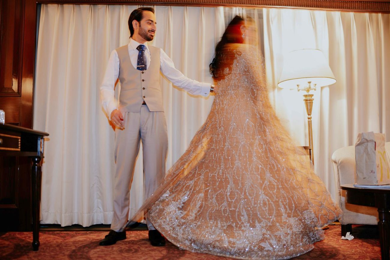 Motion-blur shot of the bride twirling, her gown flaring out, groom watching and laughing