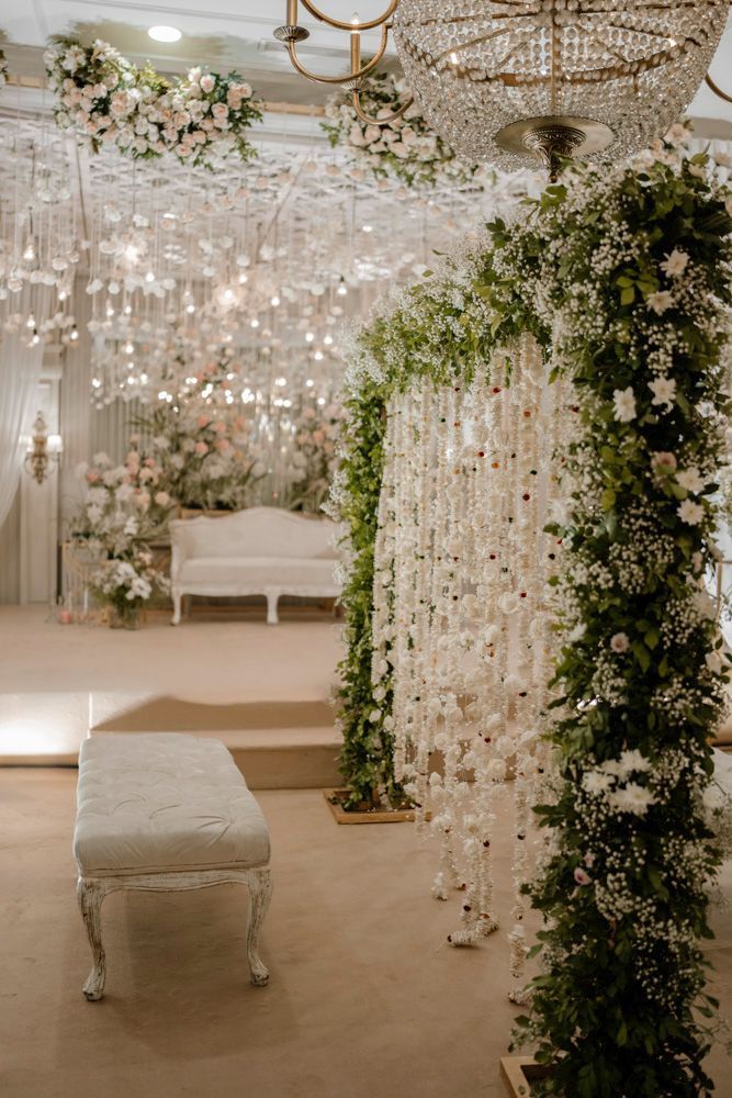 Wide view of the all-white reception hall decorated with hanging crystal chandeliers and floral installations, Sheraz & Nawal's wedding at Nishat Hotel, Lahore