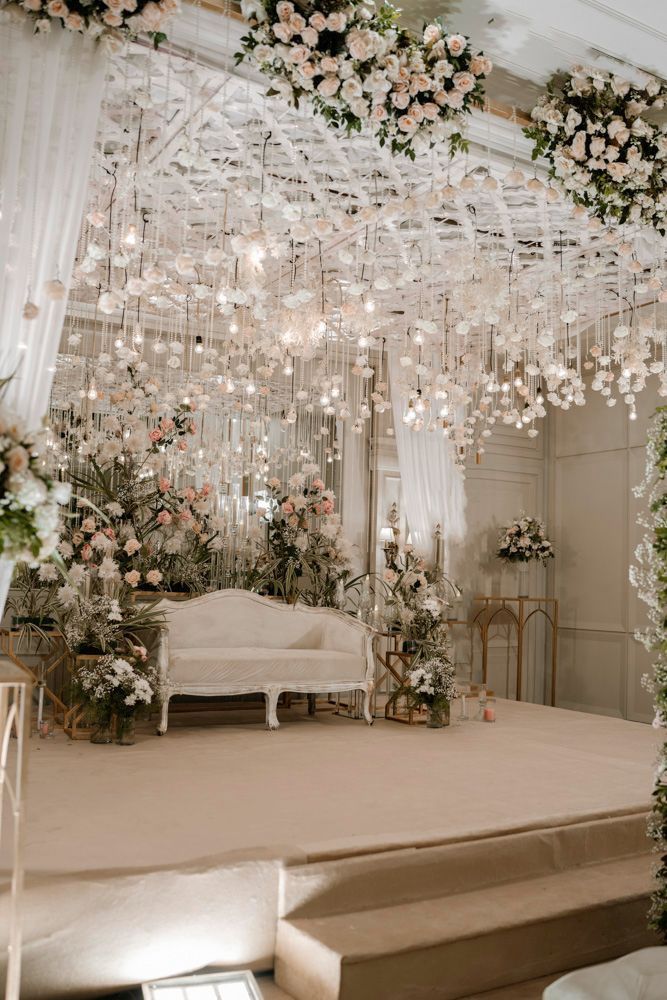 Wide shot of the reception stage with hanging floral chandeliers and a white sofa, Sheraz & Nawal's wedding at Nishat Hotel, Lahore