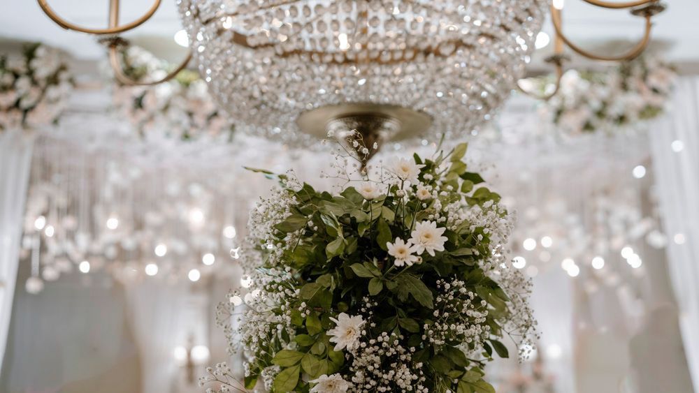 Detail of a white floral arrangement hanging beneath a crystal chandelier, Sheraz & Nawal's wedding at Nishat Hotel, Lahore