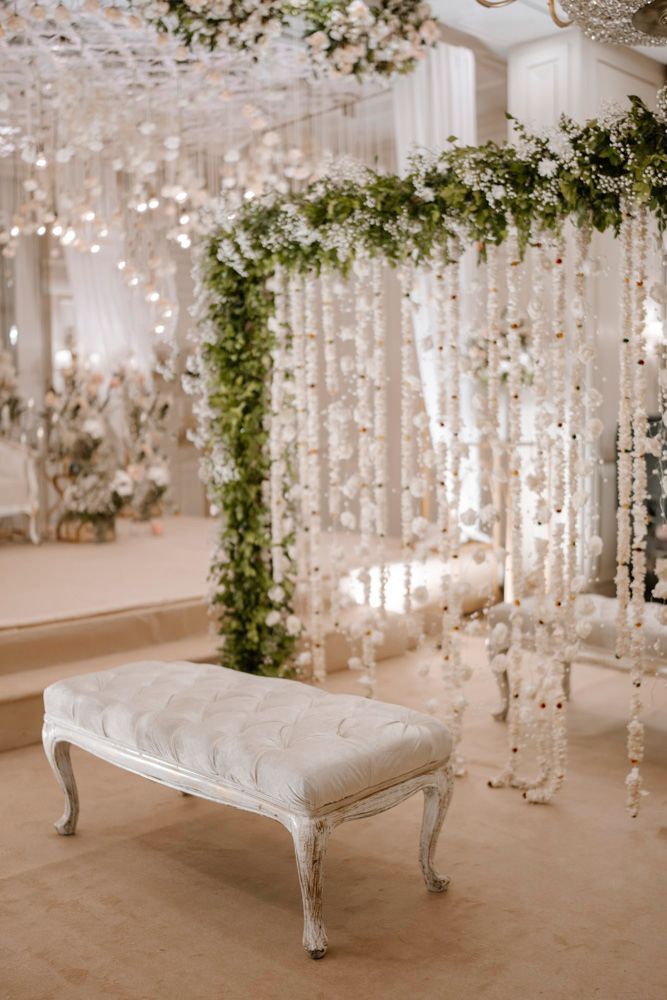 Detail of a white tufted bench beside a floral and crystal-strand archway, Sheraz & Nawal's wedding at Nishat Hotel, Lahore