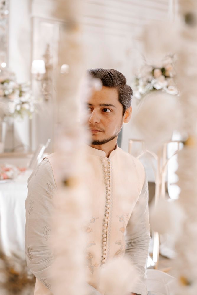 Solo groom portrait in profile, viewed through hanging floral strands, Sheraz & Nawal's wedding at Nishat Hotel, Lahore