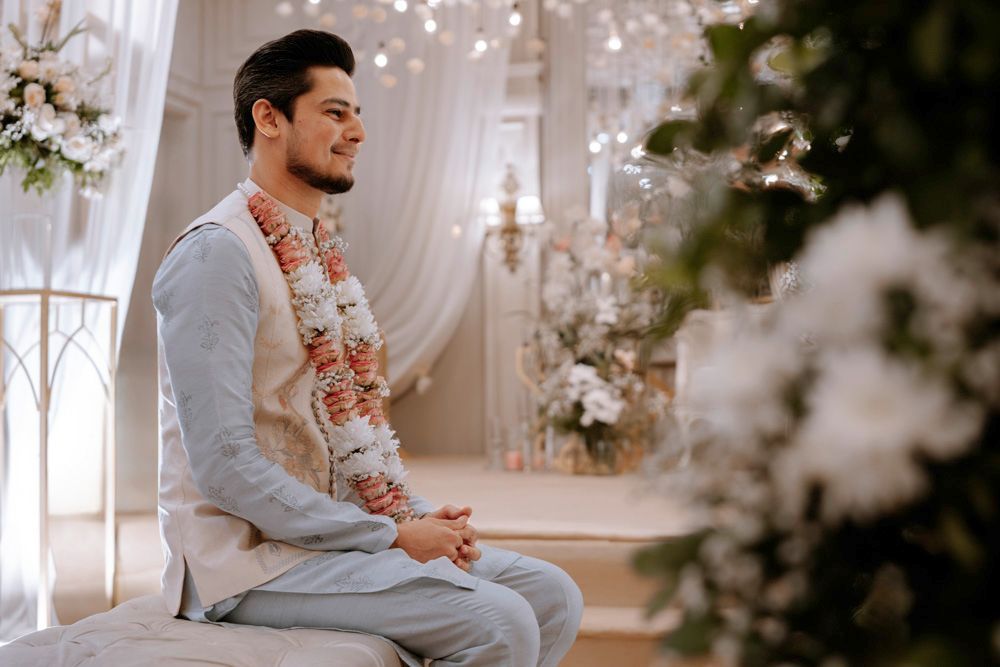 Groom smiling in profile wearing a pink and white flower garland, Sheraz & Nawal's wedding at Nishat Hotel, Lahore