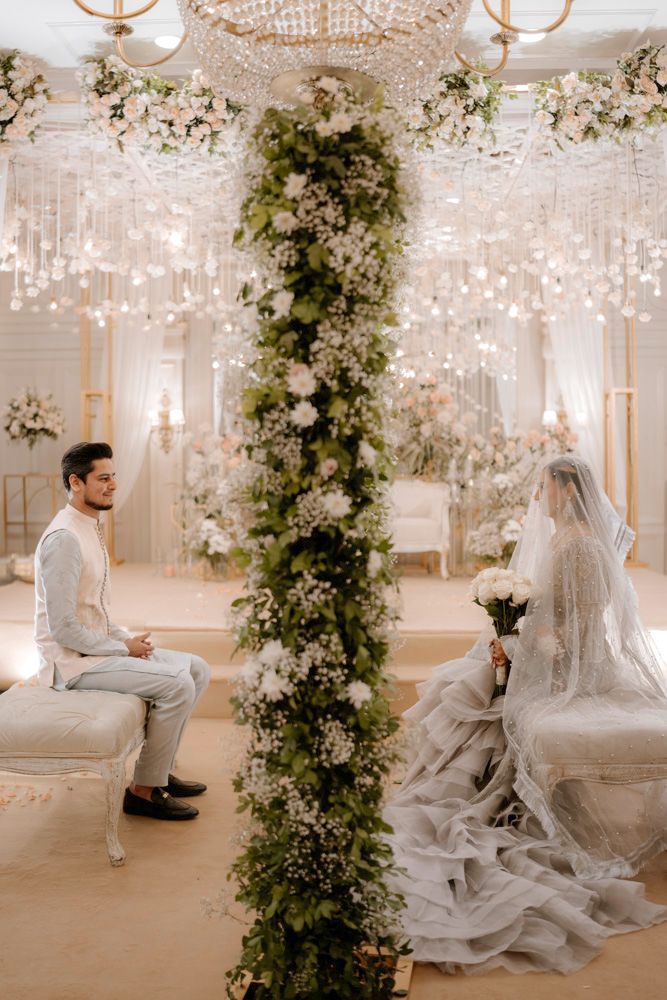 Bride and groom seated facing each other for the nikah, a tall floral column between them, Sheraz & Nawal's wedding at Nishat Hotel, Lahore