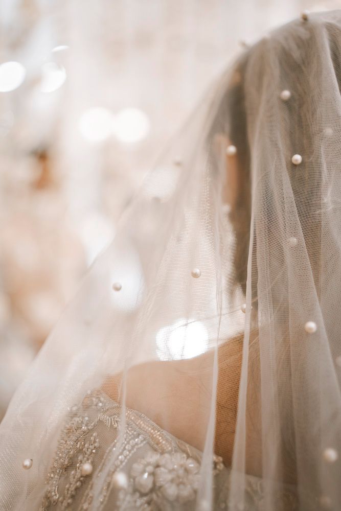 Close-up of the bride beneath her pearl-beaded veil, her embellished gown visible at the shoulder, Sheraz & Nawal's wedding at Nishat Hotel, Lahore