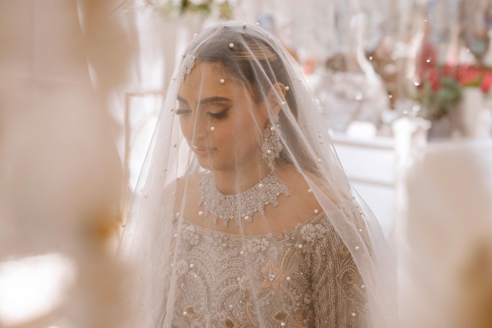 Close-up portrait of the bride beneath her veil, eyes closed, diamond necklace visible, Sheraz & Nawal's wedding at Nishat Hotel, Lahore