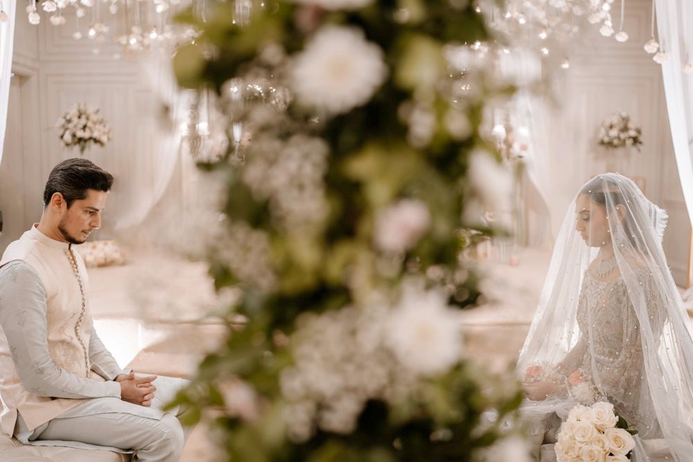 Bride and groom seated facing each other for the nikah, a floral column between them, Sheraz & Nawal's wedding at Nishat Hotel, Lahore
