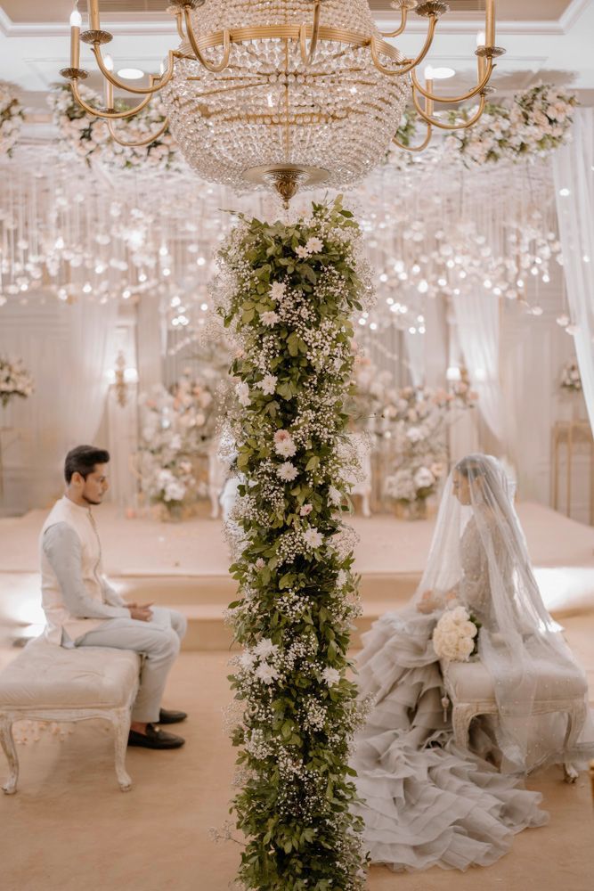 Bride and groom seated for the nikah beneath a crystal chandelier and floral column, Sheraz & Nawal's wedding at Nishat Hotel, Lahore