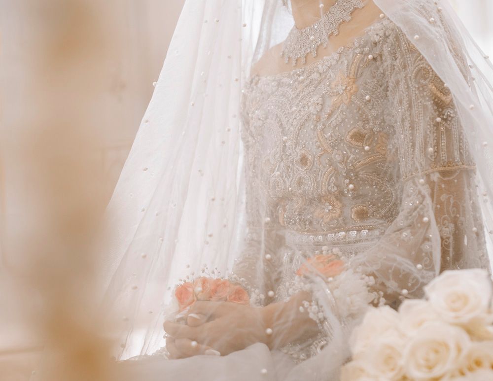 Close-up of the bride beneath her veil holding a white rose bouquet, eyes closed, Sheraz & Nawal's wedding at Nishat Hotel, Lahore