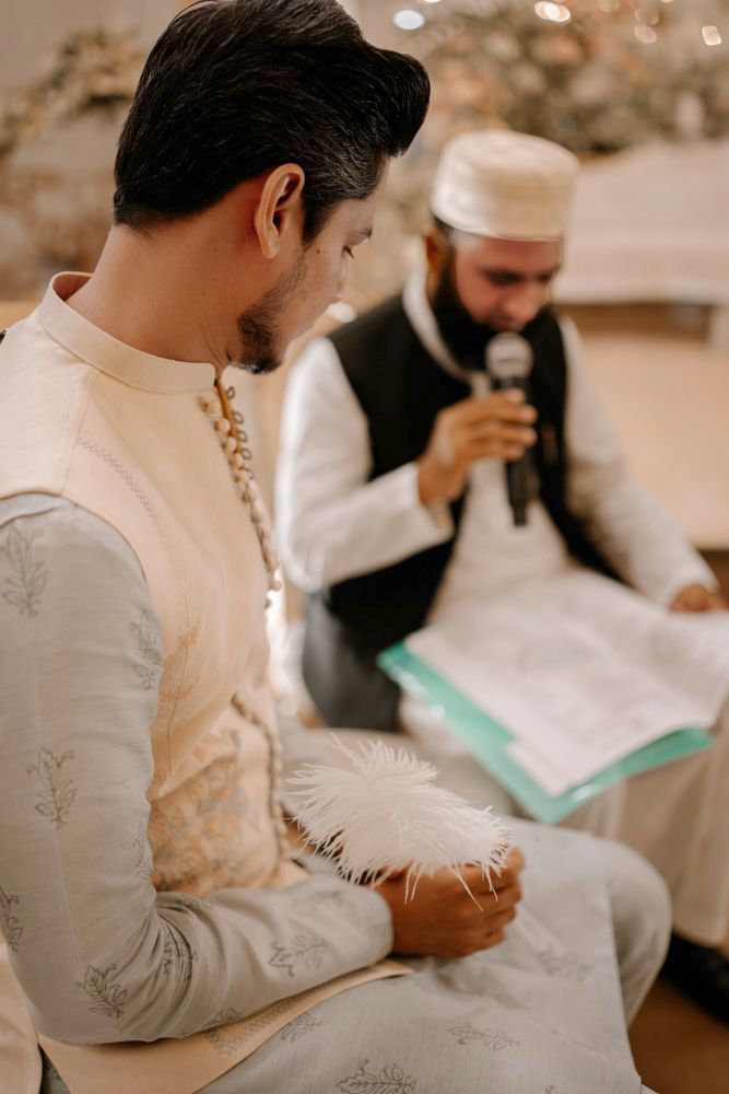 Groom seated beside the officiant holding the nikah register and a microphone, Sheraz & Nawal's wedding at Nishat Hotel, Lahore