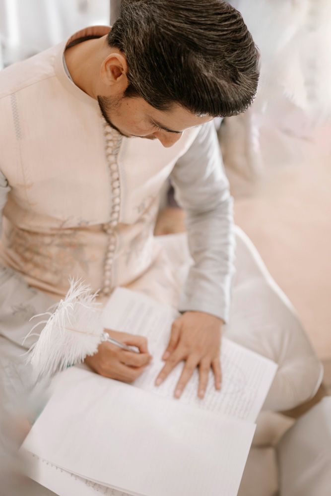 Close-up of the groom signing the nikah register with a white feather quill pen, Sheraz & Nawal's wedding at Nishat Hotel, Lahore