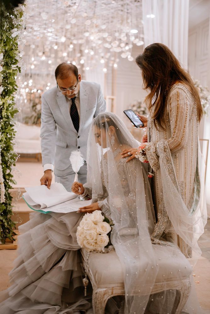 Bride signing the nikah register as her father and a family member look on, Sheraz & Nawal's wedding at Nishat Hotel, Lahore