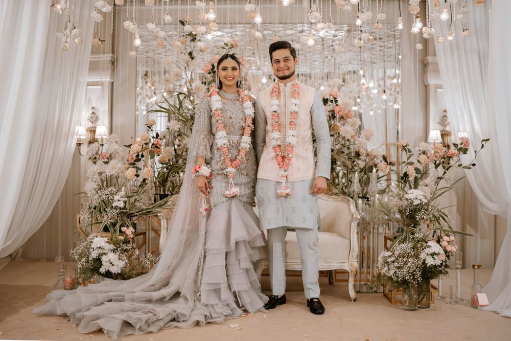 Bride and groom standing together wearing matching pink and white flower garlands, Sheraz & Nawal's wedding at Nishat Hotel, Lahore