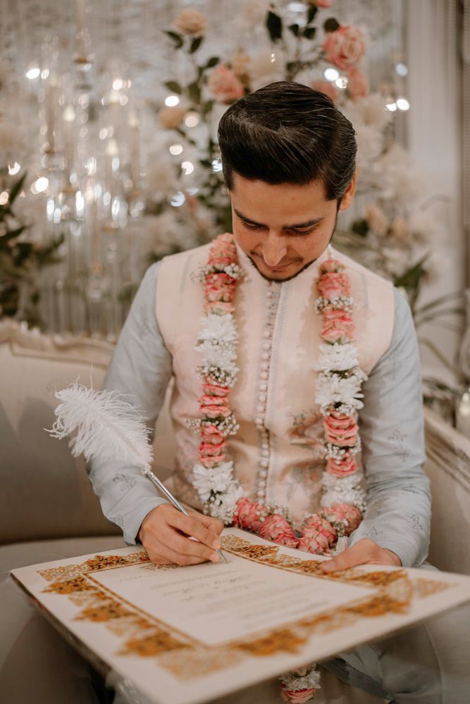 Groom signing the nikah certificate wearing a flower garland, Sheraz & Nawal's wedding at Nishat Hotel, Lahore