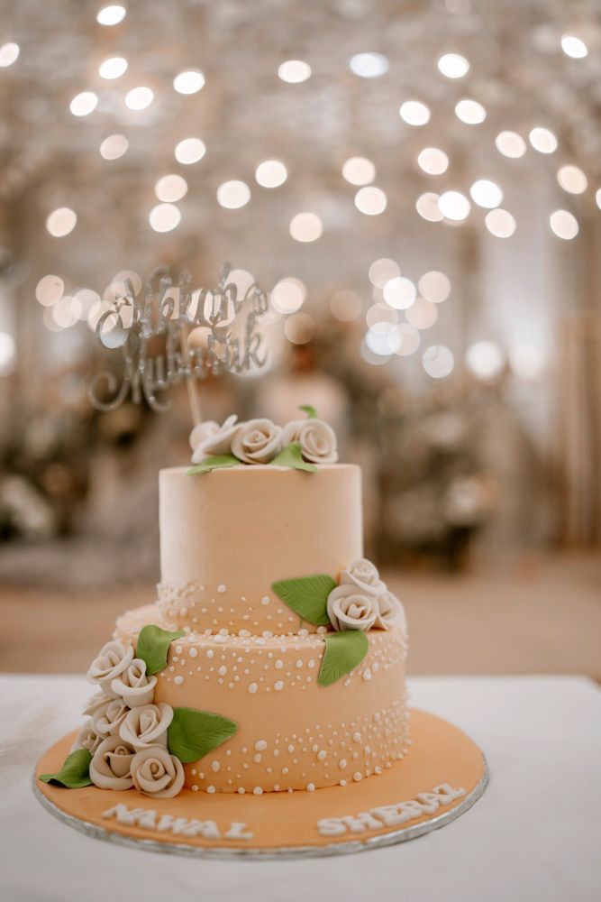 Detail of the two-tier wedding cake with a Nikkah Mubarak topper and sugar roses, names Nawal and Sheraz on the base, Sheraz & Nawal's wedding at Nishat Hotel, Lahore
