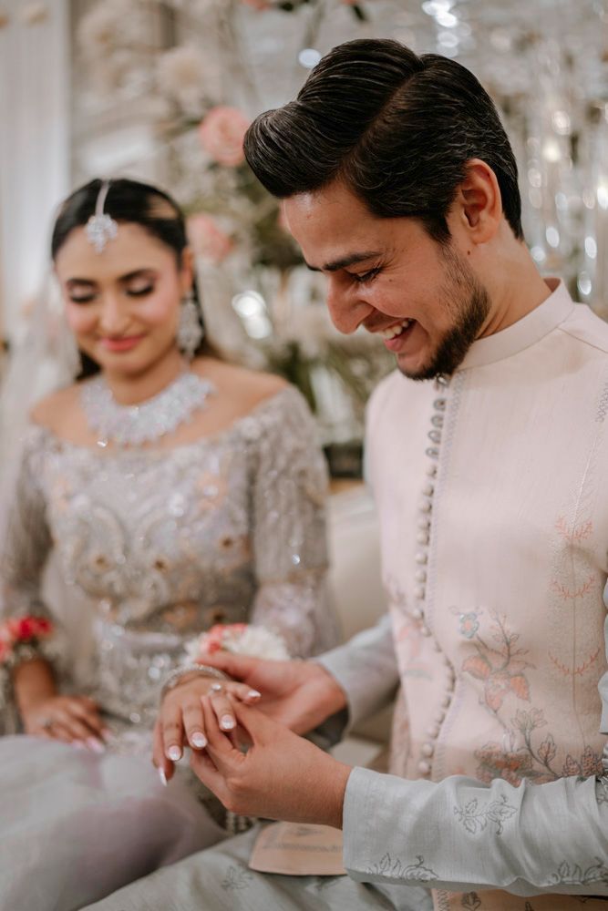 Close-up of groom laughing as he places a ring on the bride's finger, Sheraz & Nawal's wedding at Nishat Hotel, Lahore