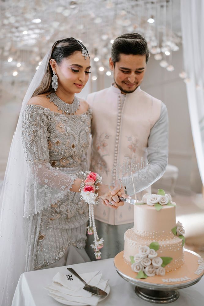 Bride and groom cutting their two-tier wedding cake together, smiling at each other, Sheraz & Nawal's wedding at Nishat Hotel, Lahore