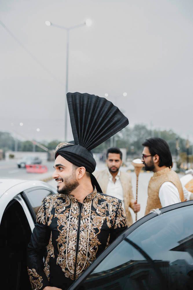 Groom in his black embroidered sherwani and turban stepping into a car, candid smile, Zara & Shuaib's wedding, Lahore