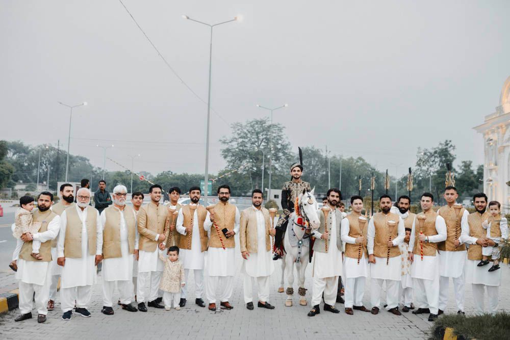 Groom on the decorated horse surrounded by family members holding ceremonial maces, Zara & Shuaib's wedding, Lahore
