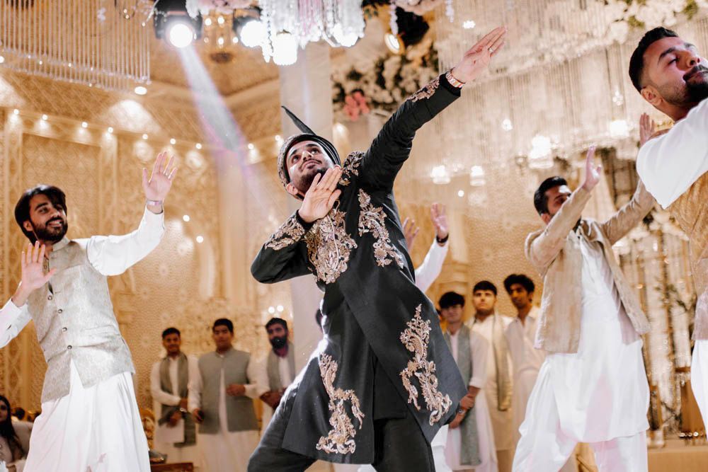 Groom dancing among friends on the reception floor, arm raised, Zara & Shuaib's wedding at Garrison Halls, Lahore