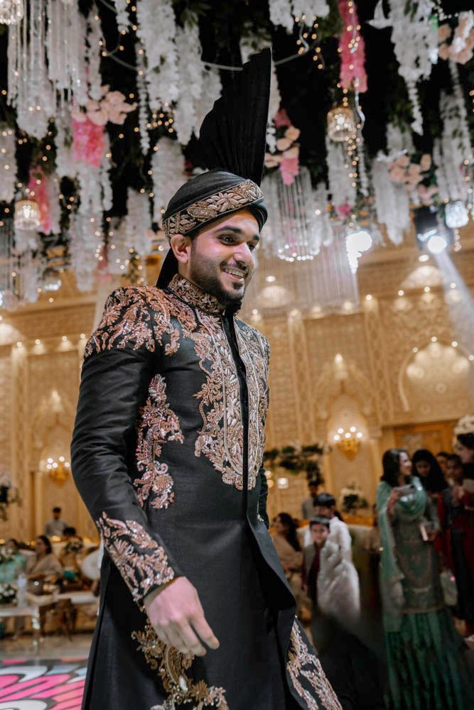 Close-up of the groom smiling mid-dance beneath hanging floral chandeliers, Zara & Shuaib's wedding at Garrison Halls, Lahore