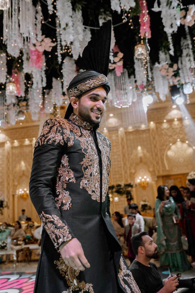 Groom smiling during his dance performance, hanging floral decor behind him, Zara & Shuaib's wedding at Garrison Halls, Lahore