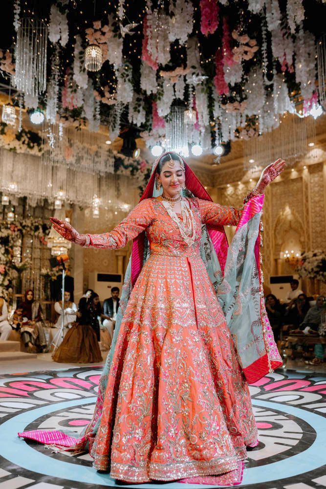 Bride dancing with arms outstretched on the patterned reception floor, Zara & Shuaib's wedding at Garrison Halls, Lahore
