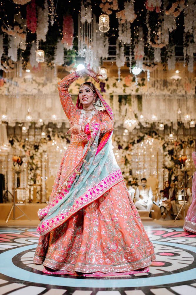 Bride dancing with one arm raised overhead, smiling, Zara & Shuaib's wedding at Garrison Halls, Lahore