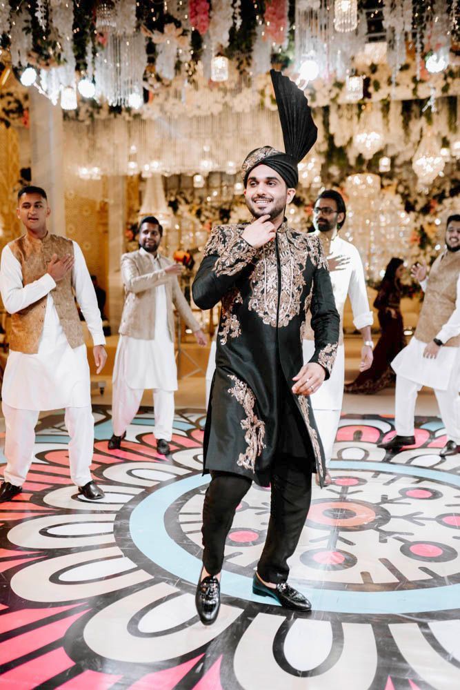 Groom dancing on the patterned floor with friends clapping around him, Zara & Shuaib's wedding at Garrison Halls, Lahore