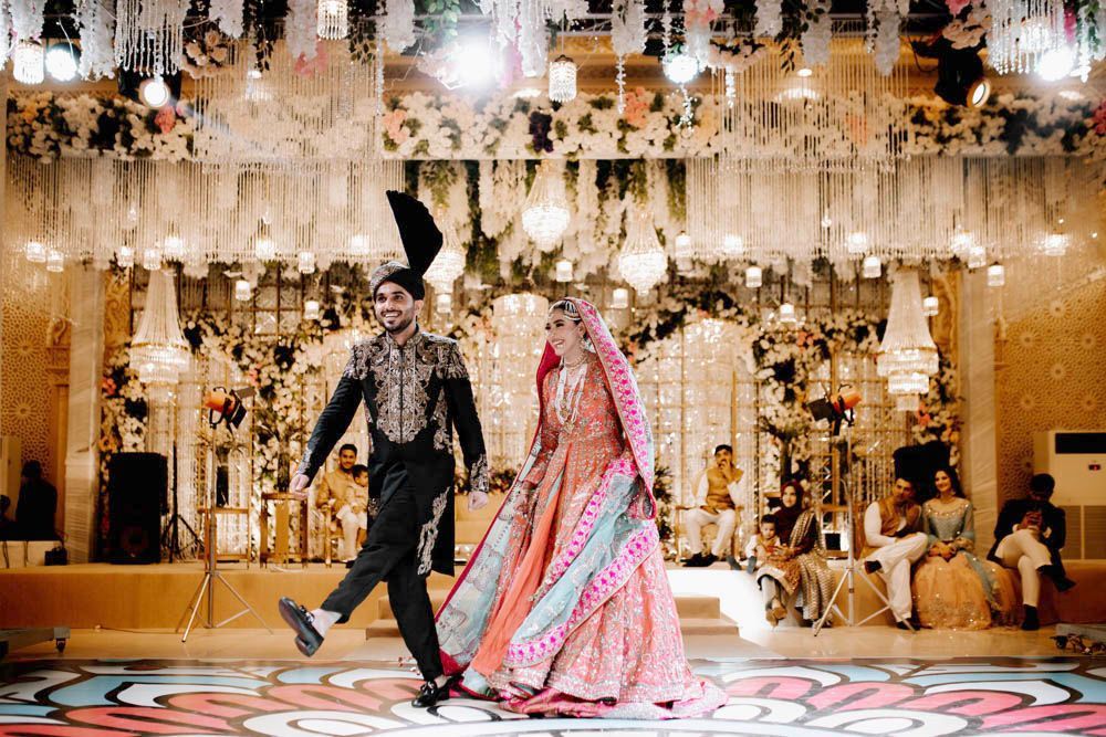 Bride and groom walking together onto the dance floor, holding hands, Zara & Shuaib's wedding at Garrison Halls, Lahore