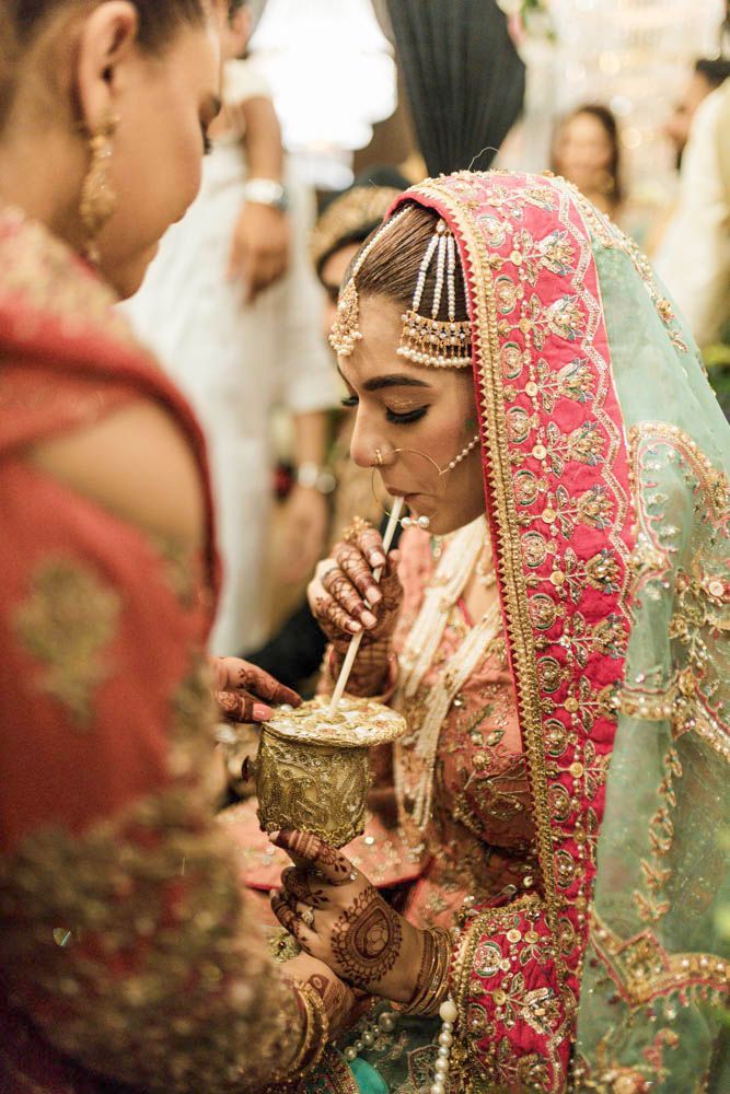 Close-up of the bride sipping from the ornate cup, henna-painted hands visible, Zara & Shuaib's wedding, Lahore