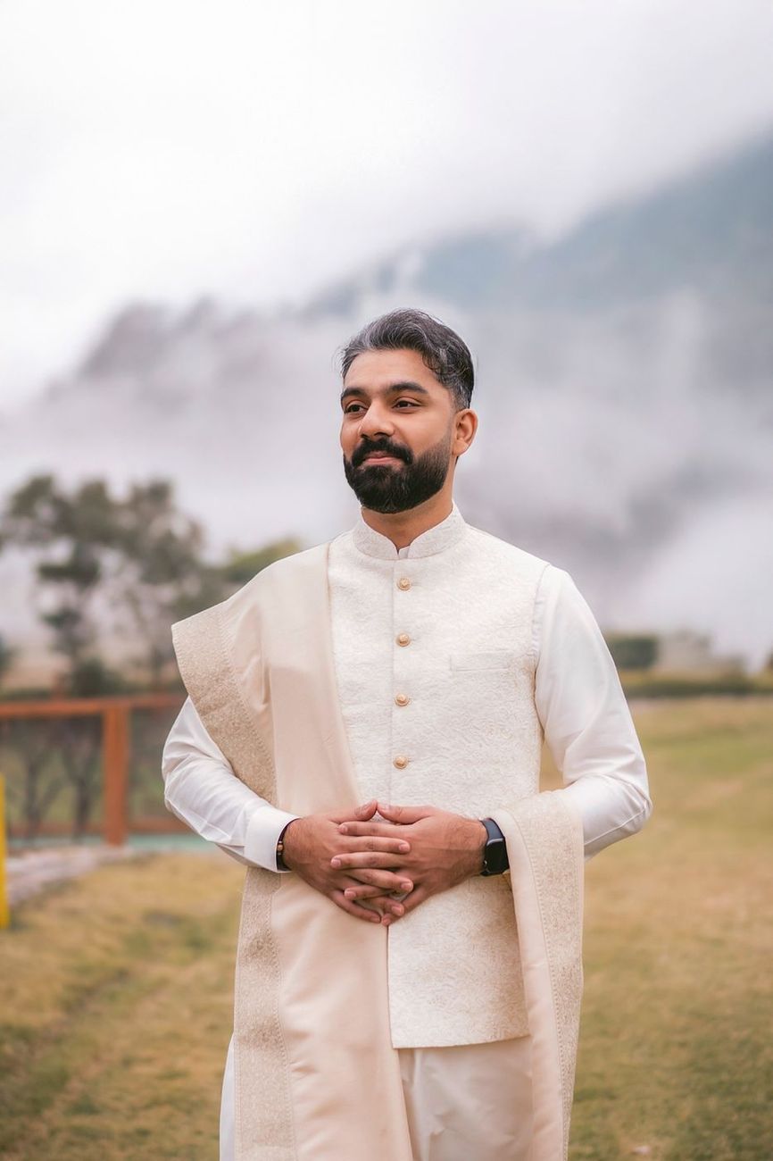 Solo portrait of the groom with fog-covered hills directly behind him