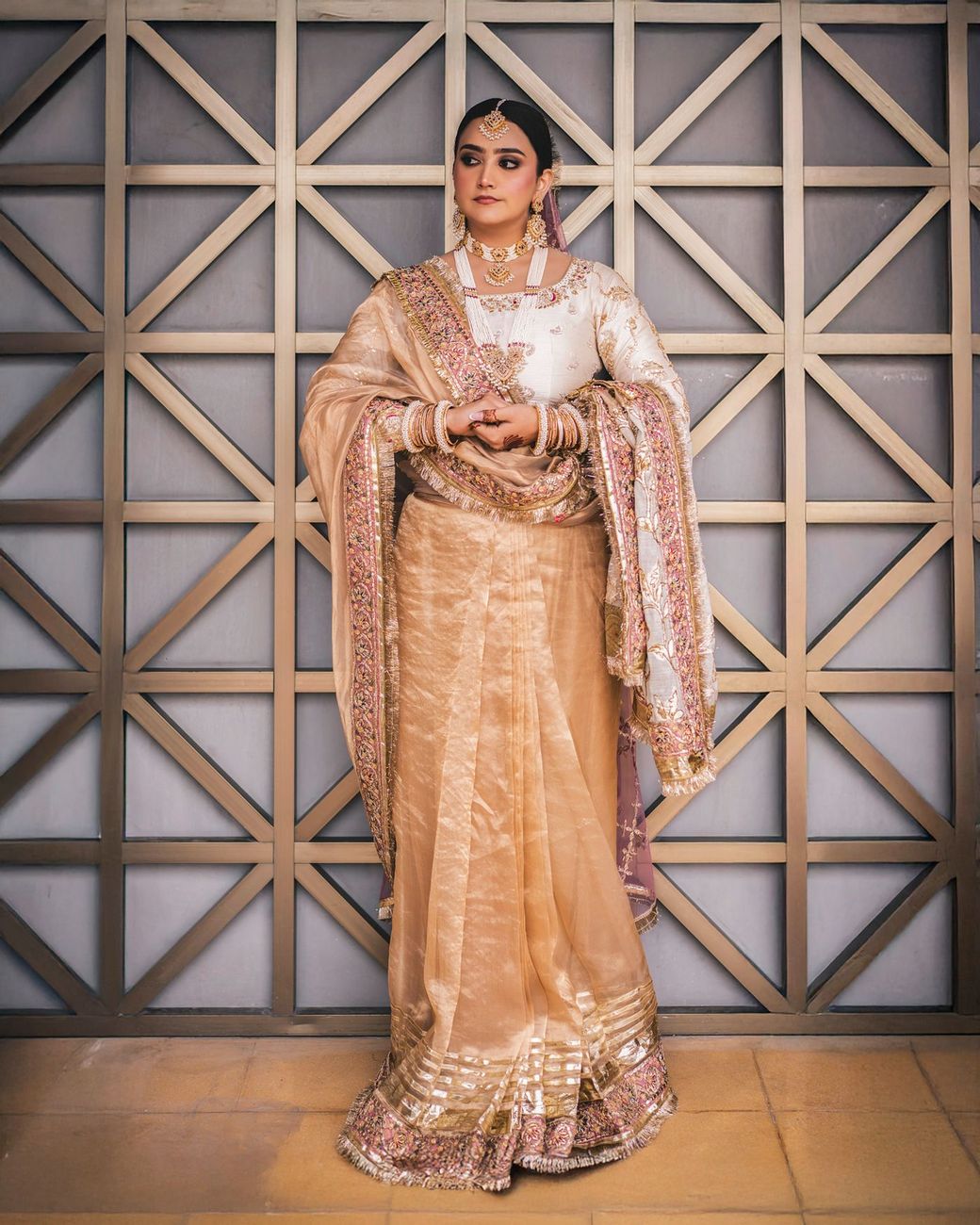 Solo bridal portrait against a geometric latticed gold-and-grey wall
